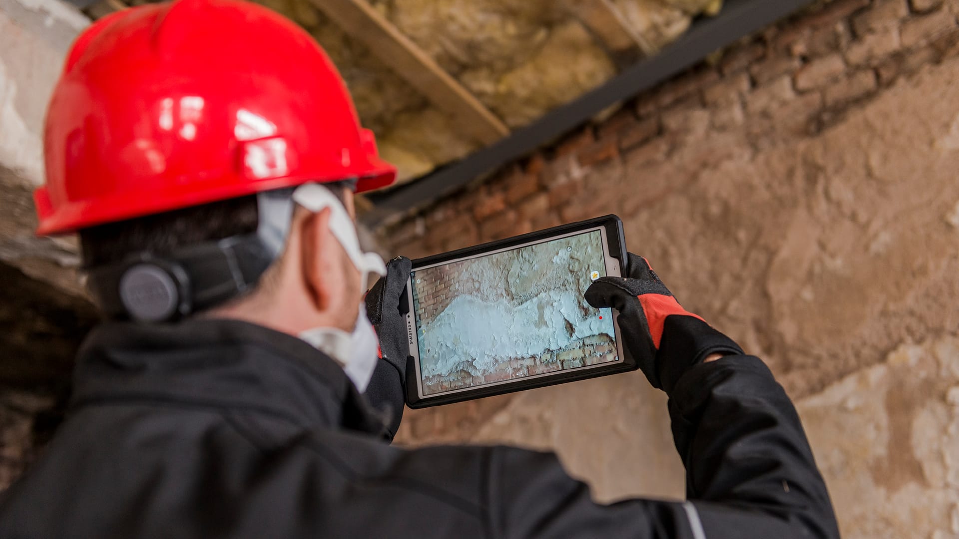 Ein männlicher Angestellter nutzt ein Tablet, um die Schäden an einem Gebäude zu bewerten