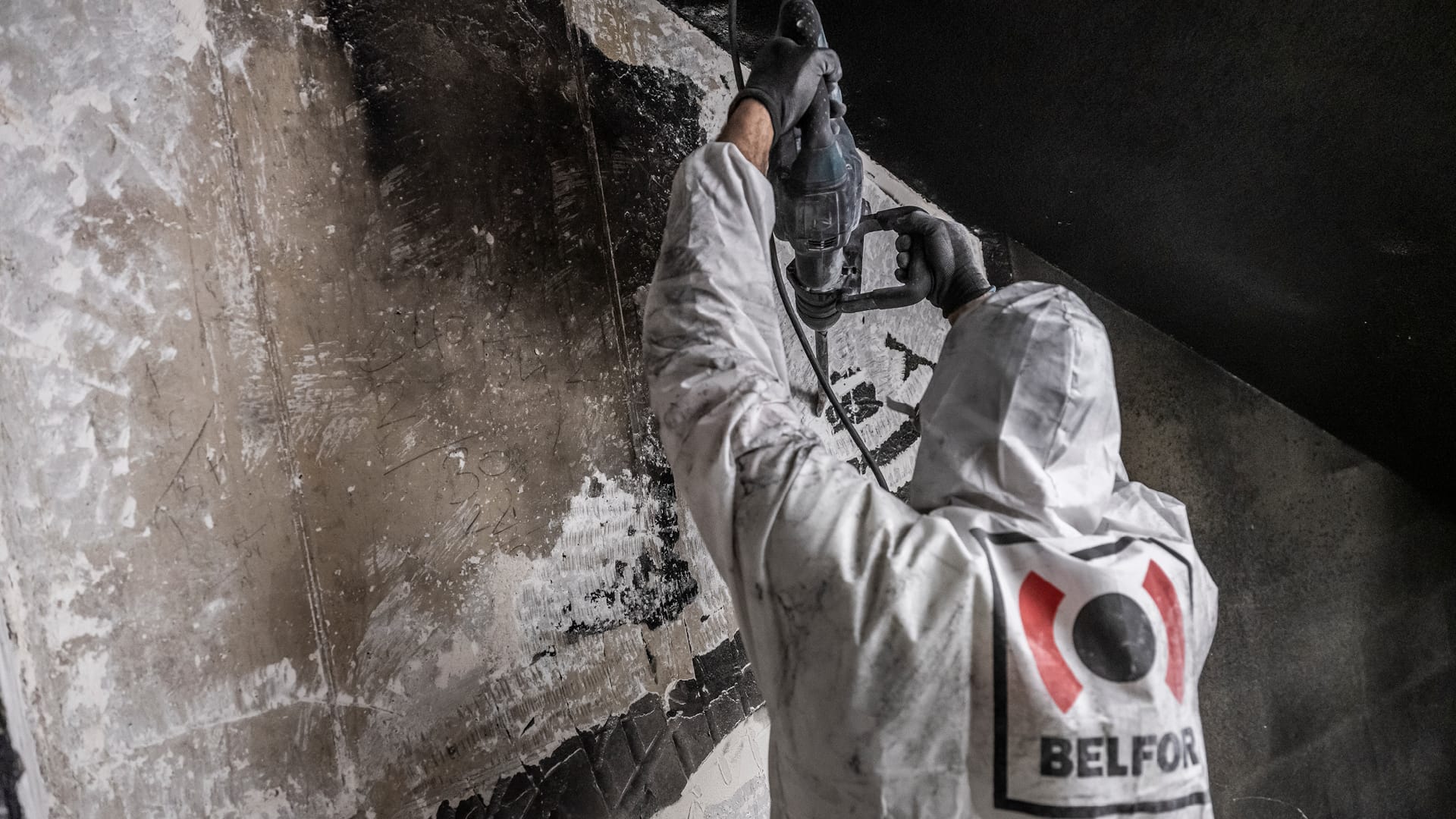 Een BELFOR-medewerker boort een beschadigde muur