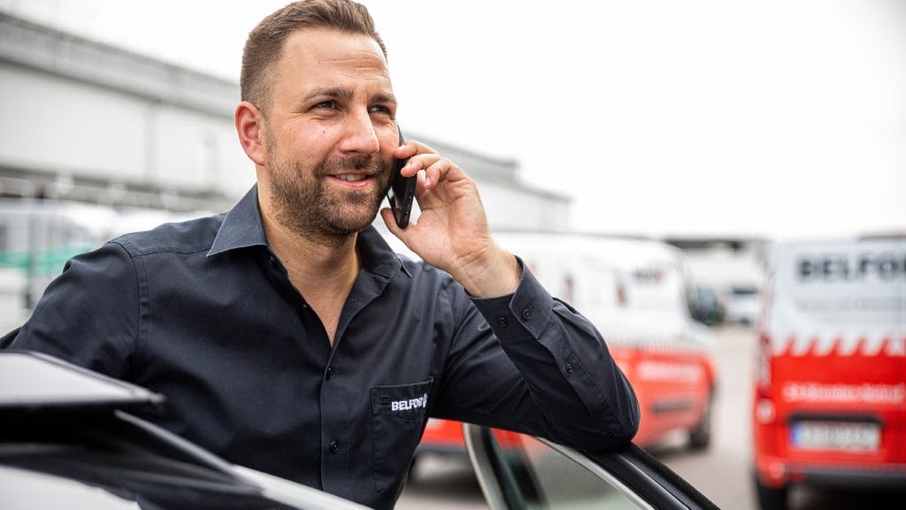 Een BELFOR-projectmanager lacht terwijl hij met iemand aan de telefoon praat