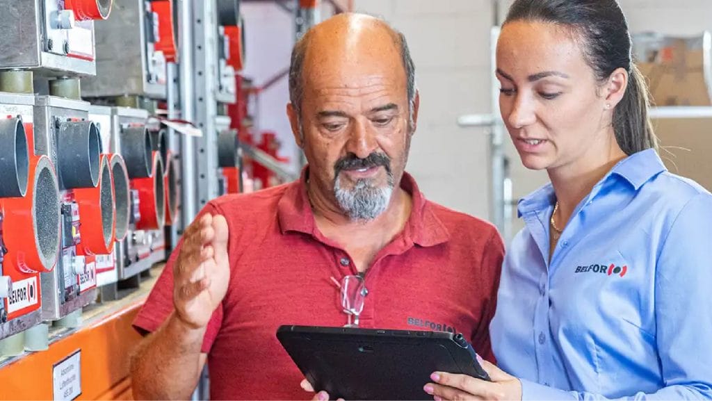 Un homme et une femme regardent une tablette dans un entrepôt.