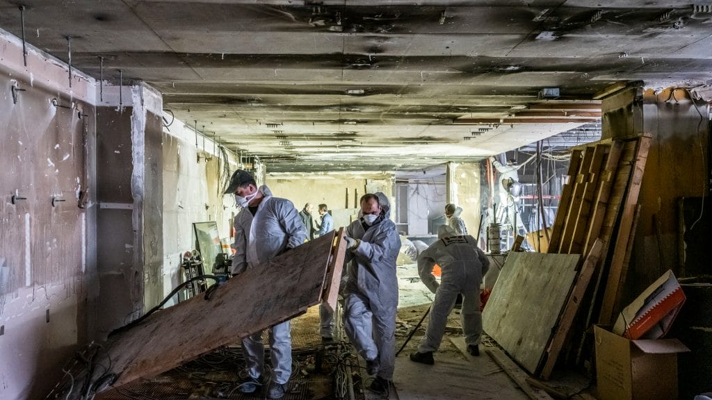 Des ouvriers réparent des panneaux muraux endommagés sur un chantier de construction.