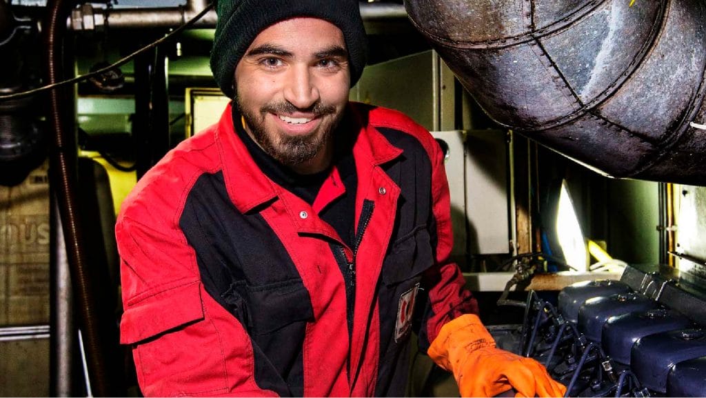 Un homme en veste rouge et gants orange sourit