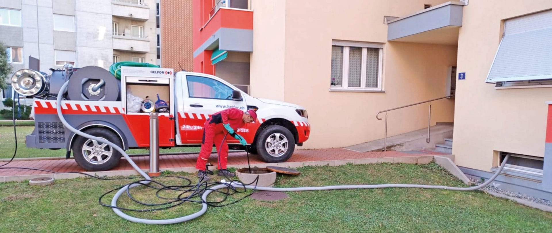 Un uomo in rosso si trova davanti a un'auto e pulisce un canale