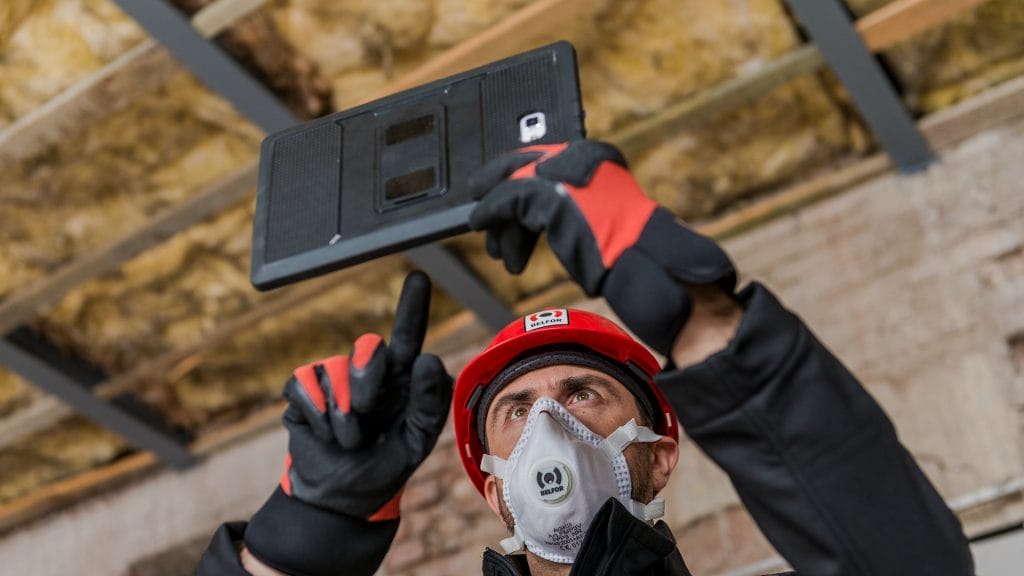 A BELFOR employee wearing PPE and taking images