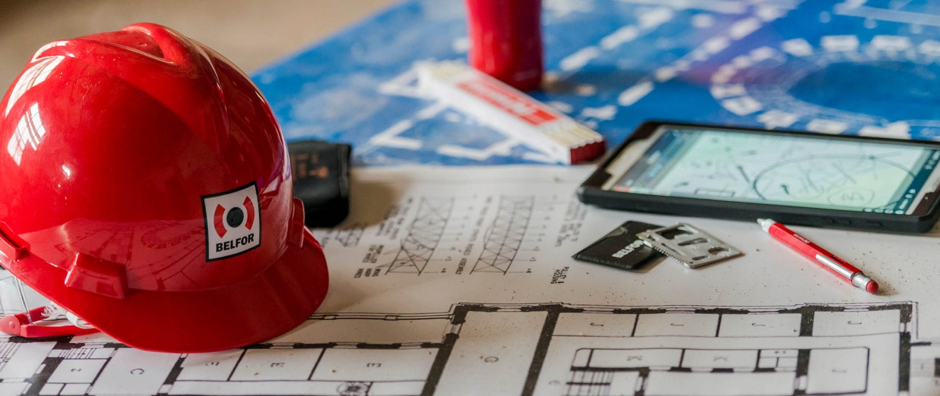 A BELFOR hard hat and blueprint on the table