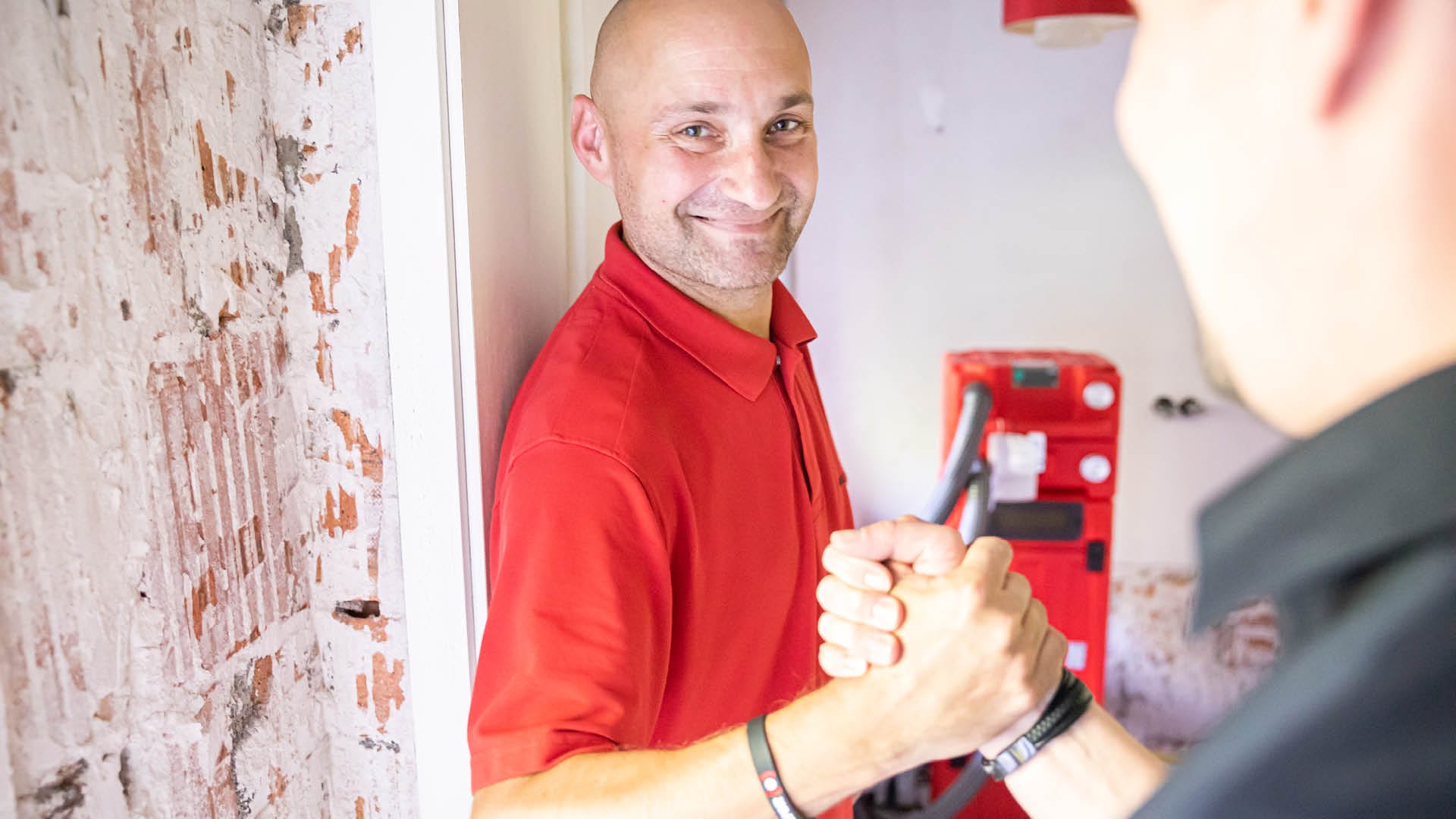 A male employee smiling while shaking another person's hand