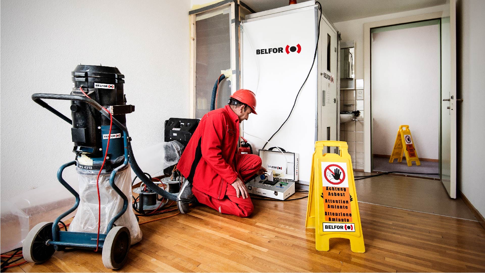 A man in red standing next to a machine