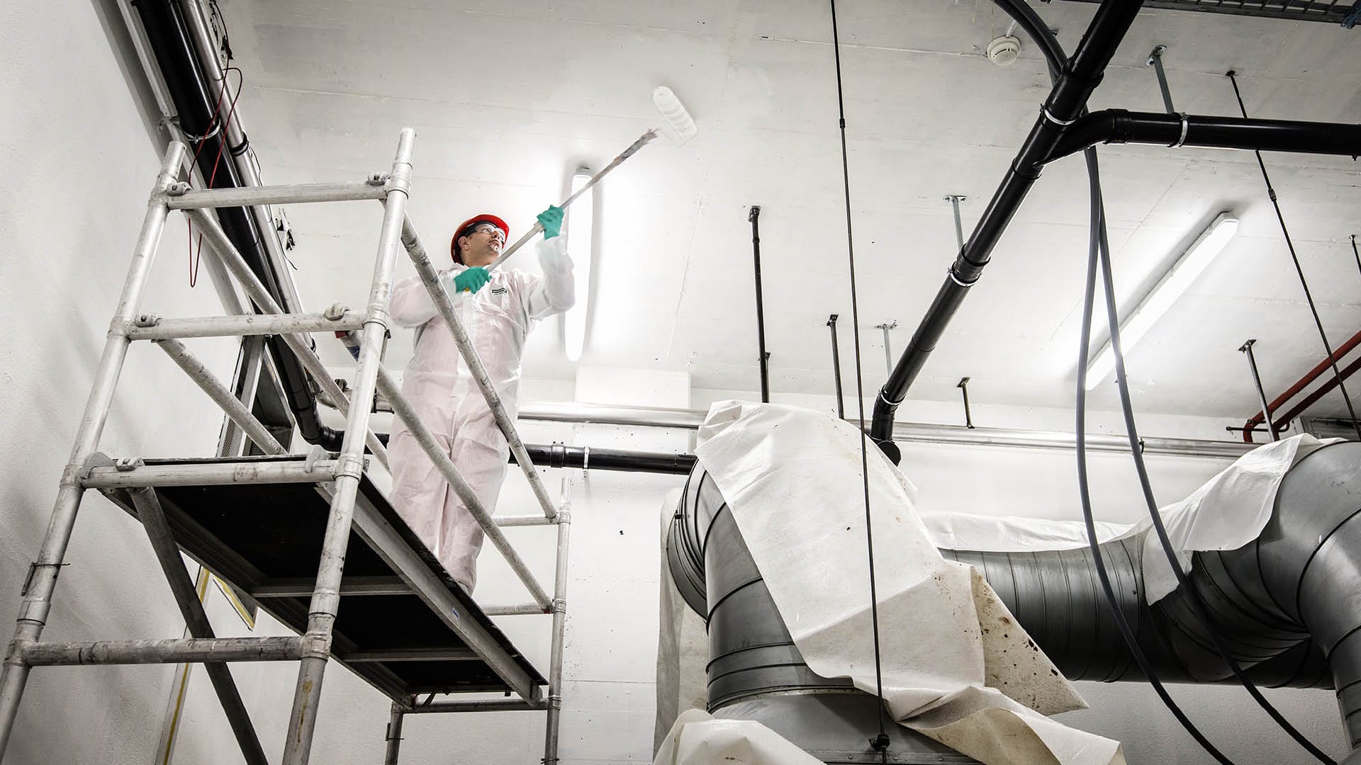 Un imbianchino BELFOR dipinge il soffitto di un edificio industriale