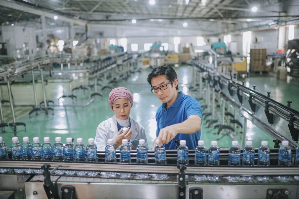 A woman and a man in fromt of a bottle production line