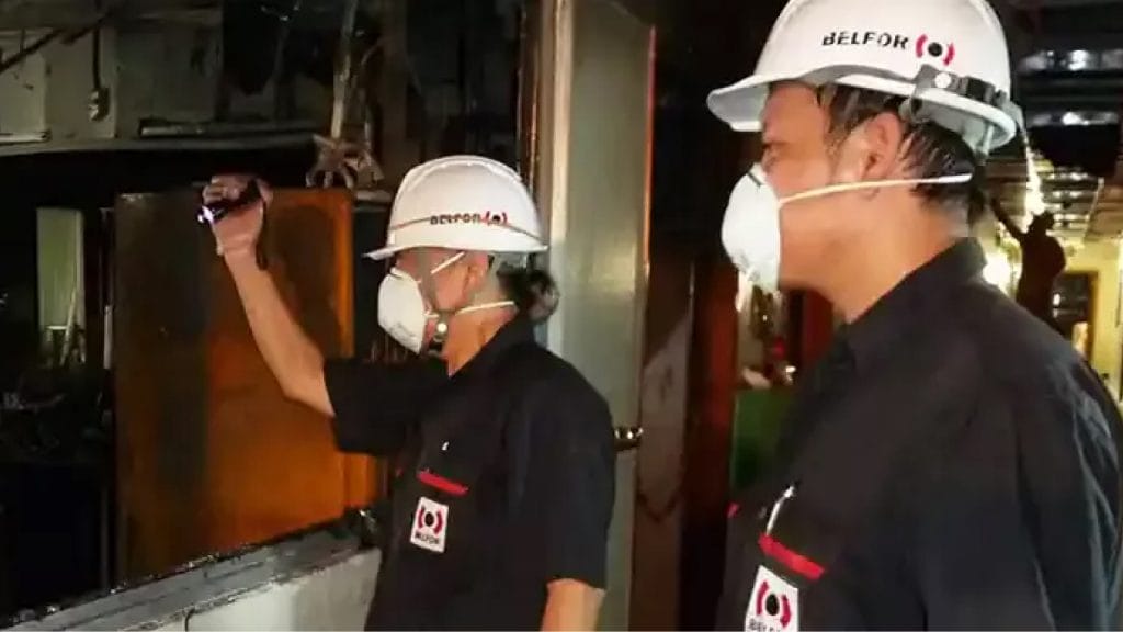 Two BELFOR employees with hard helmets ans face mask doing an inspection