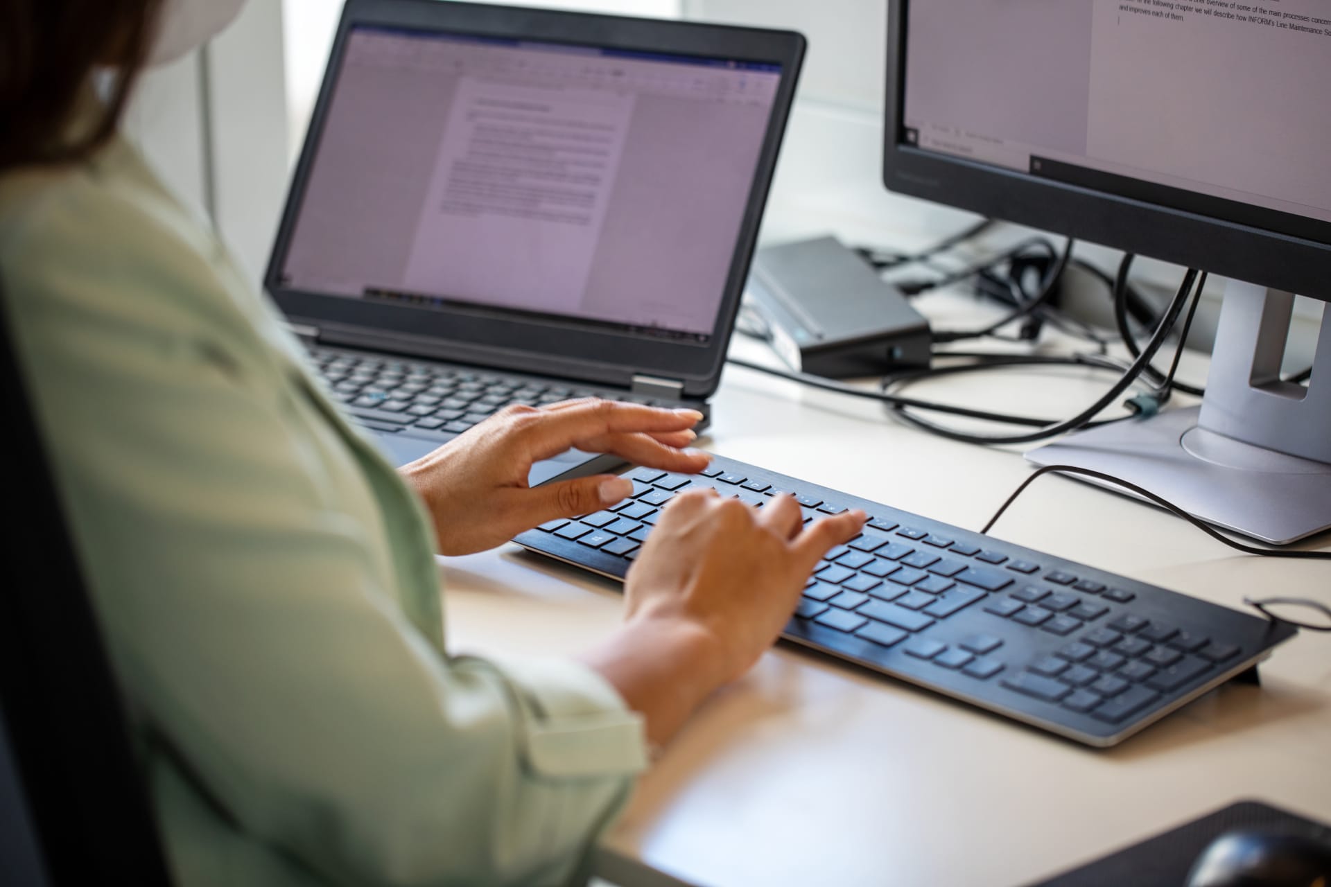 Close-up of woman typing on computer keyboard at workplace. Businesswoman using desktop computer in office.