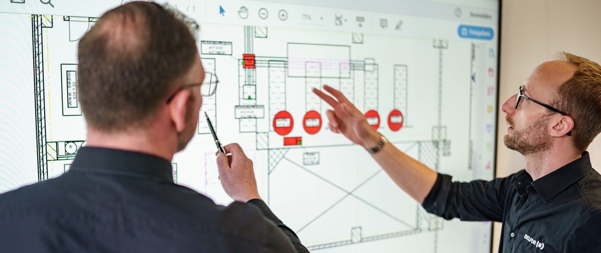 Två BELFOR-projektledare framför en skärm