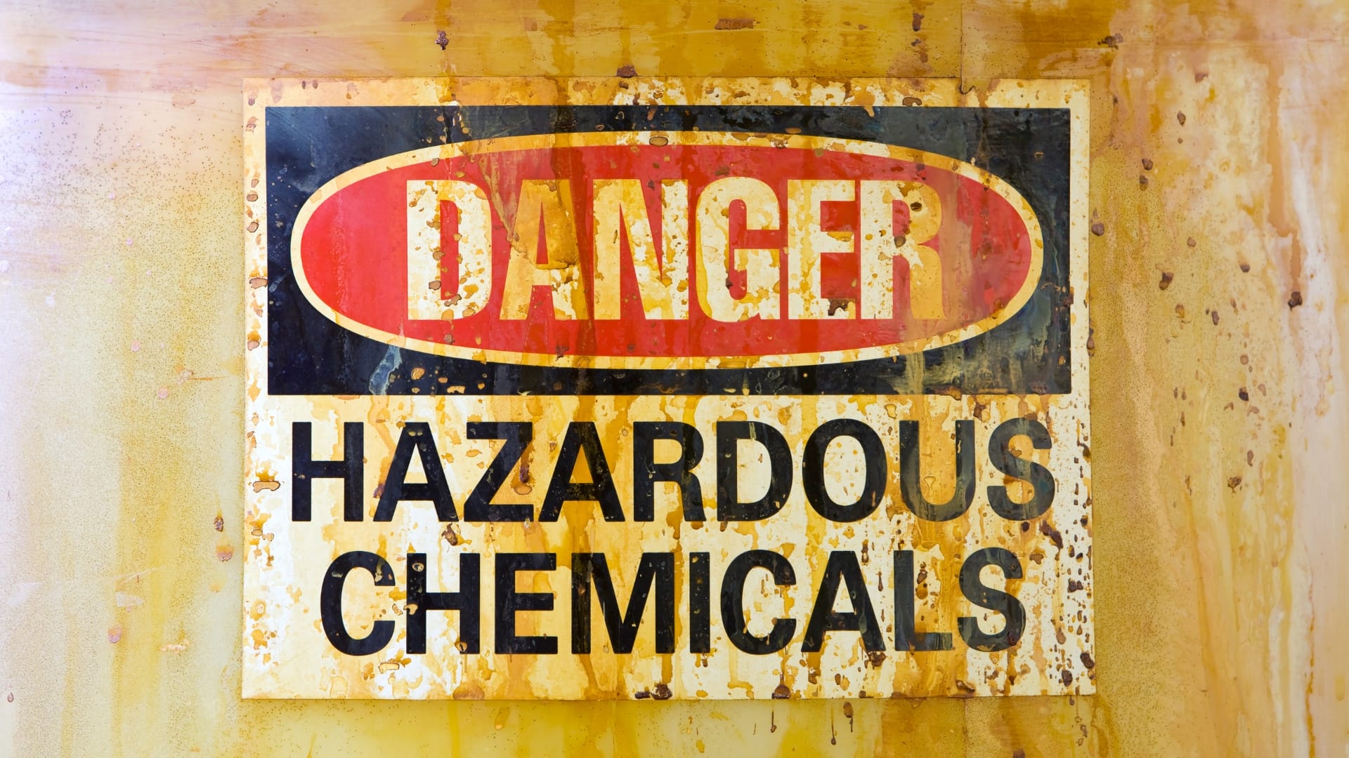 rusty sign stating danger hazardous chemicals highlighting the risks associated with the area.