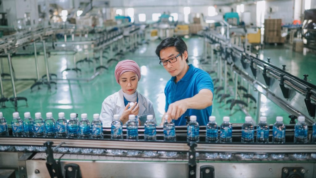 A woman and a man in fromt of a bottle production line