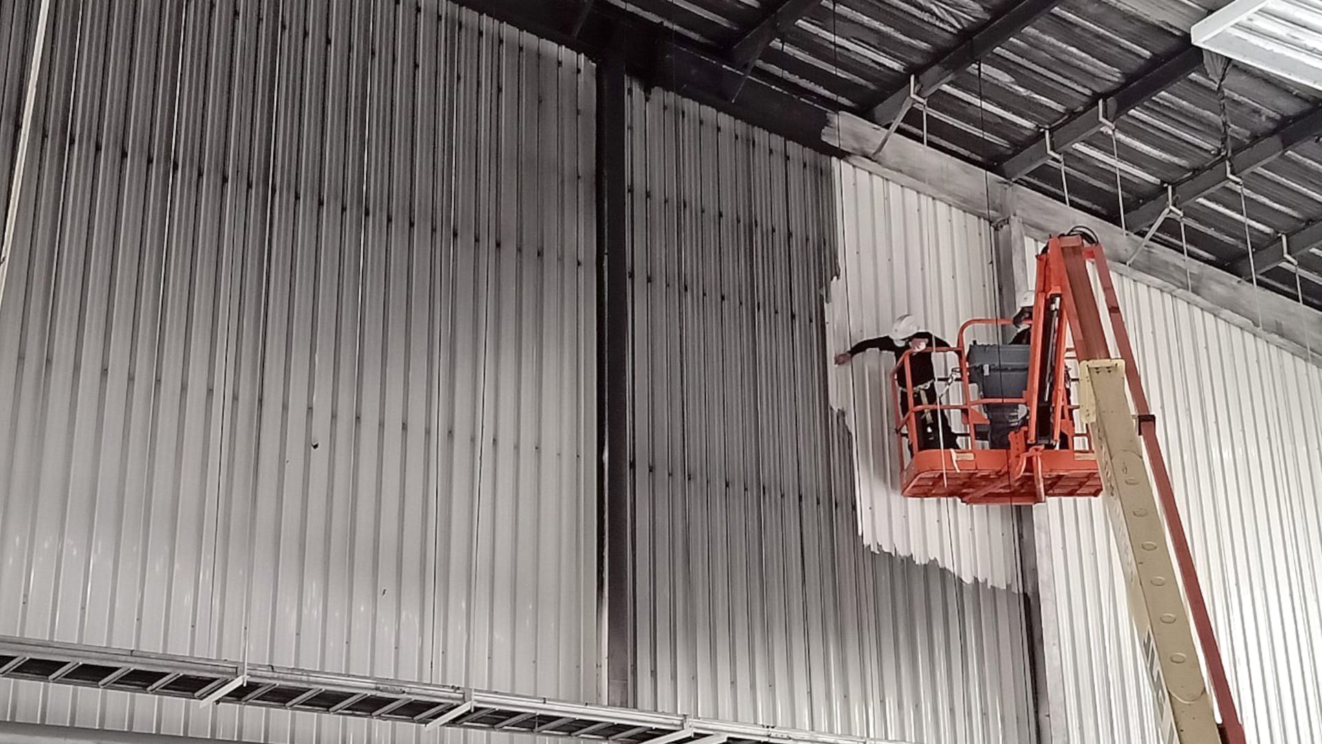 An employee is is applying Soot Removal Film on a wall while on a lifting equipment