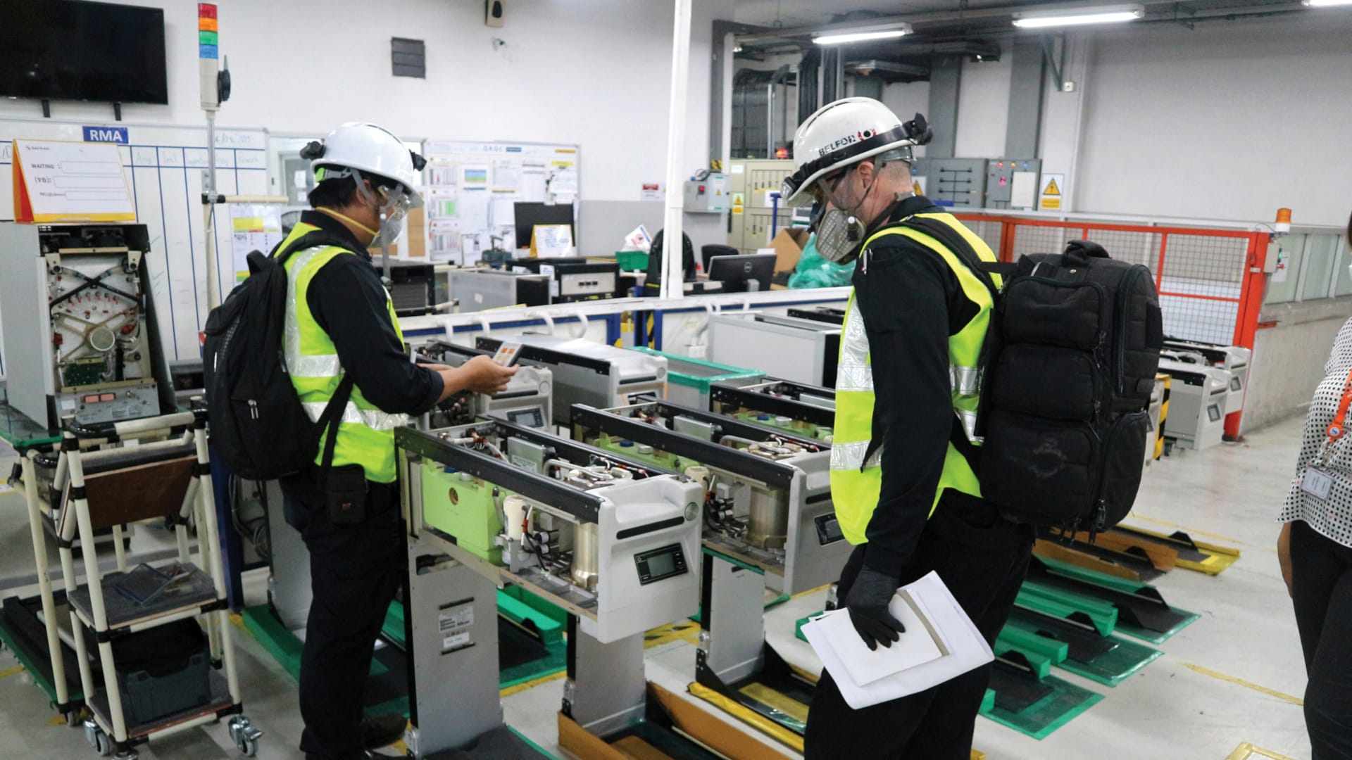 Two empoyees with helmets inspecting a machine