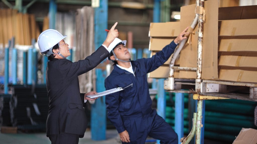 Two people with hard hats in a warehouse