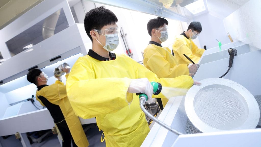 BELFOR employees in yellow overalls cleaning semiconductor parts_