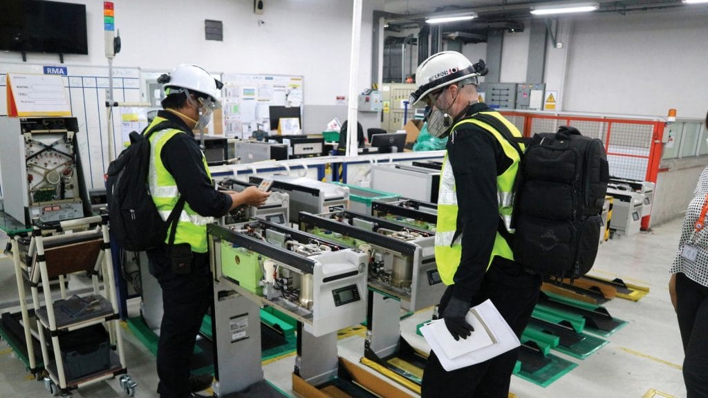 BELFOR employees with helmets inspecting a machine