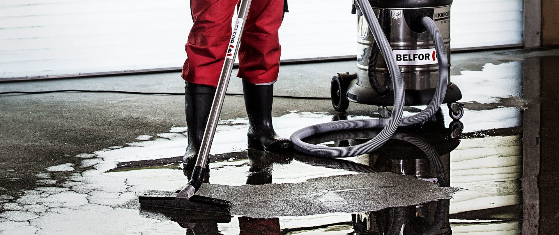 A BELFOR employee removing water using a vacuum cleaner