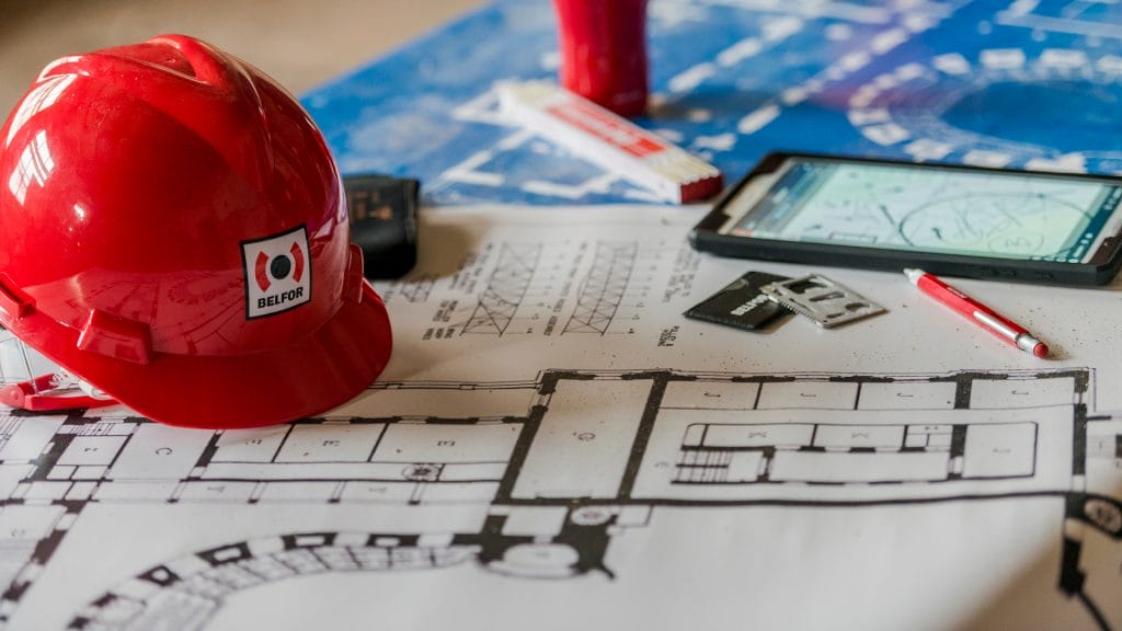 A BELFOR hard hat and blueprint on the table