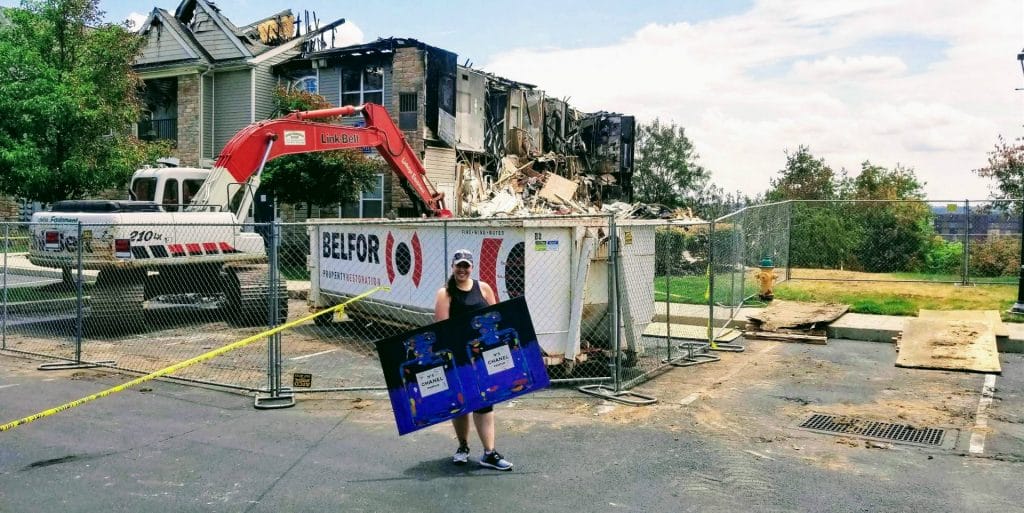 A woman holding a sign with a BELFOR sign in the background