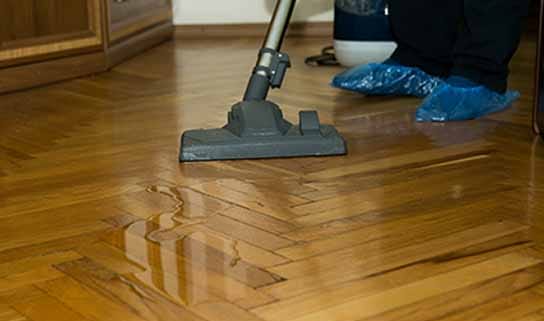 A person extracting water from a flooded floor