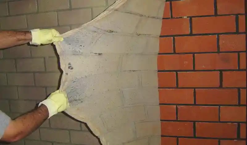 An expert removes soot from a wall