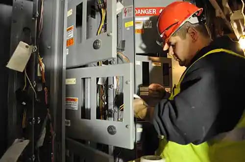 An electrical enginner works on an electricity board after a storm