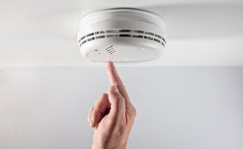 A person touching a smoke detector